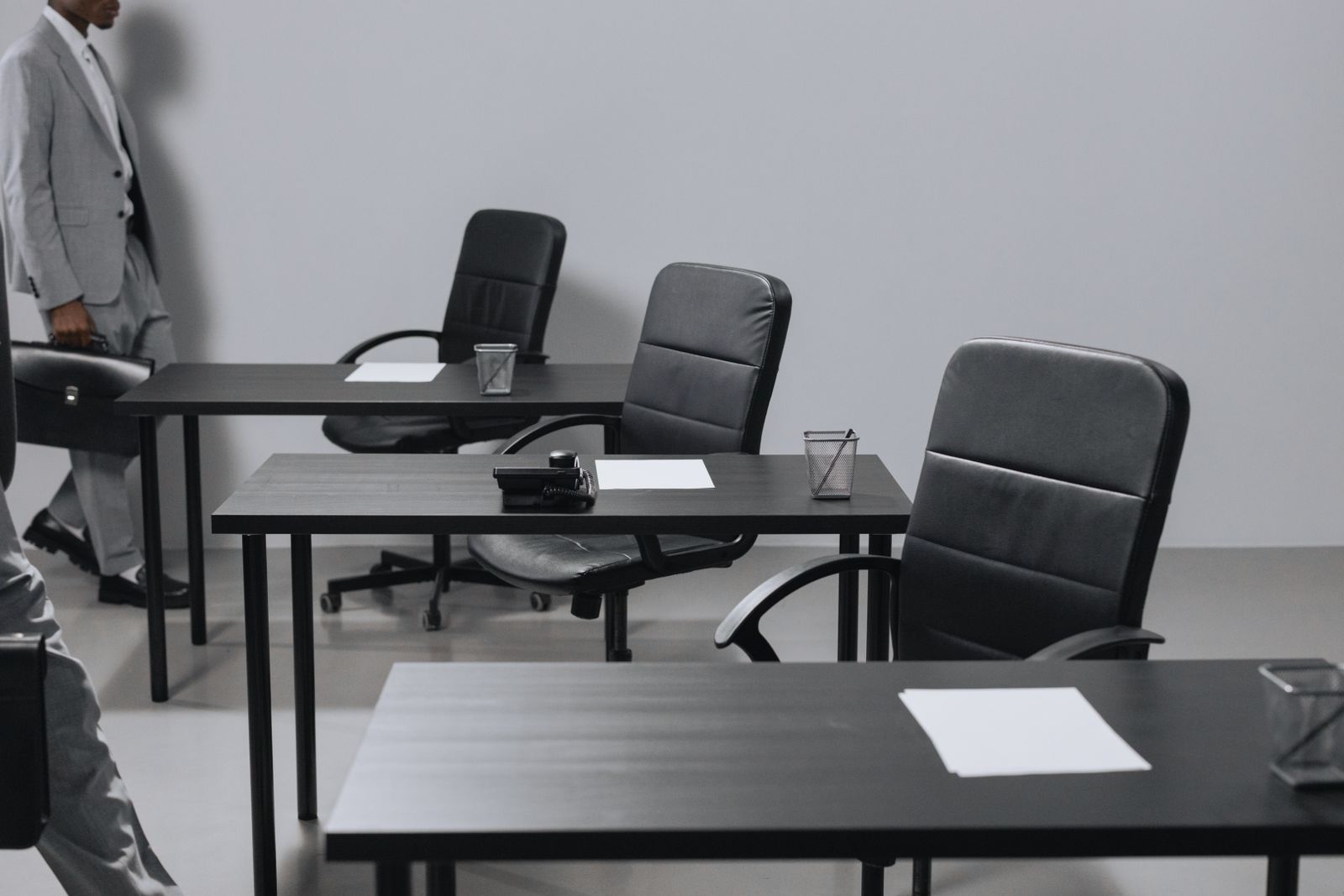 Empty office desks and chairs with a person walking past holding a briefcase, representing labor market conditions